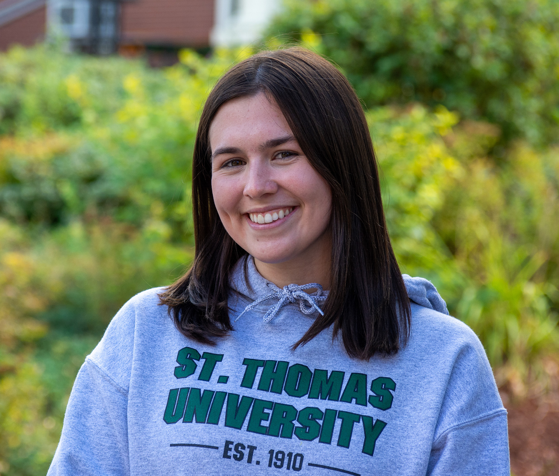 A female student with dark hearing wearing a St. Thomas University sweatshirt