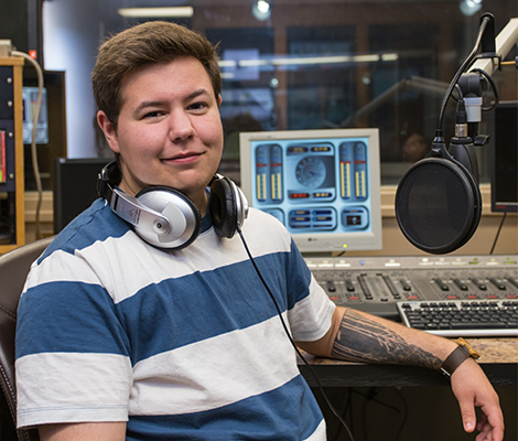 A male student sitting in a radio booth