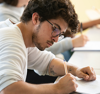 A male student writing in class at St. Thomas University
