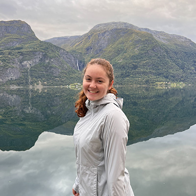 A student stands in front of scenic fjords in Norway