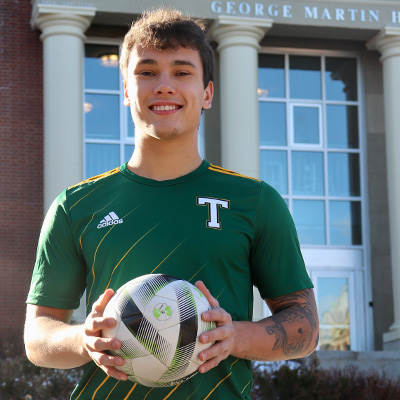 A photo of josh oakes on campus holding a soccer ball