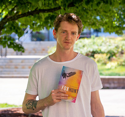 The author standing on campus holding up a copy of his book