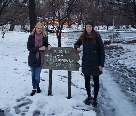 Two female students near sign board in Japan in winter