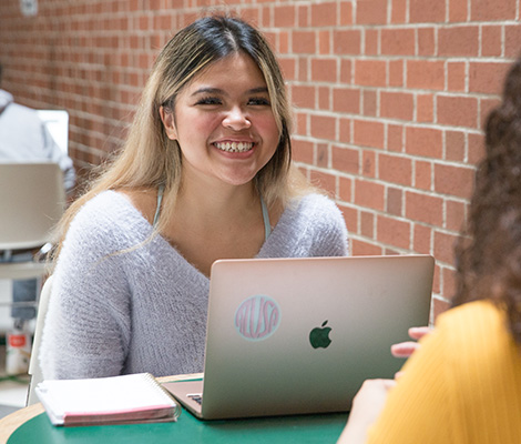 Photo of a student sitting with a laptop smiling