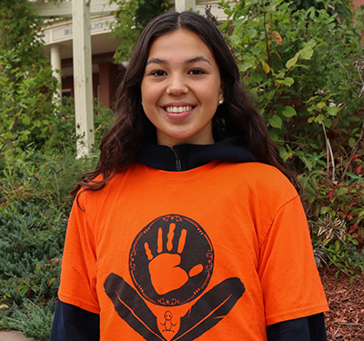 A photo of Savannah Simon on campus in an orange shirt